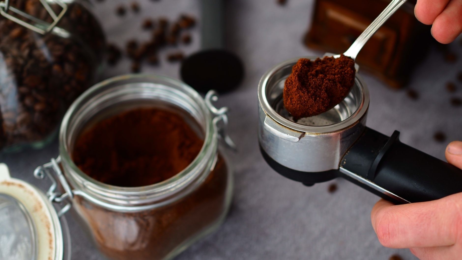 Spoonful of ground coffee held over an espresso portafilter